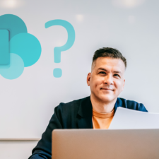 man sitting in front of white board with Microsoft SharePoint logo and question mark