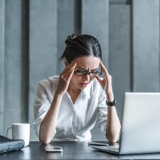 A stressed woman sitting while on her laptop | Pros and cons of SharePoint