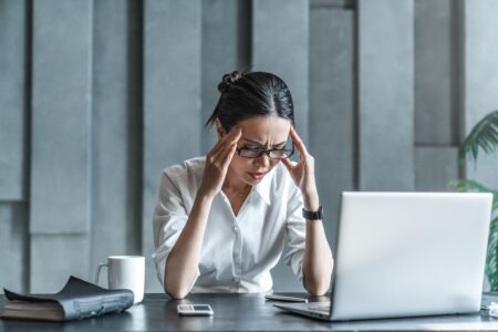 A stressed woman sitting while on her laptop | Pros and cons of SharePoint