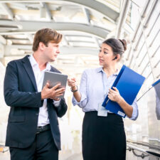 Full length of smiling business people discussing about a meeting while walking in the city.