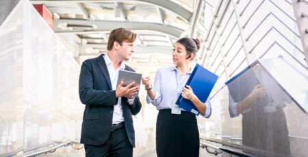 Full length of smiling business people discussing about a meeting while walking in the city.